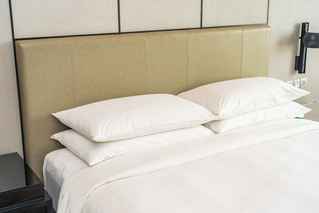 L'Importance de la Literie en Location Saisonnière : Un Facteur Clé pour des Avis 5 Étoiles 2 Lit double avec matelas confortable, draps en coton blanc et oreillers moelleux dans une chambre élégante de location saisonnière.